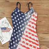 Woman wearing a sleeveless dress with distressed American flag print, taking a mirror selfie with stars on one side and red stripes on the other.

